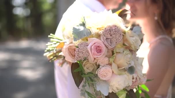 Наречена і наречений обіймаються, наречена тримає весільний букет в руках, крупним планом — стокове відео