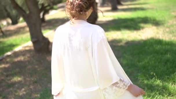 Жінка в витонченому пігноїрі гуляє по оливковому гаю в літній день — стокове відео