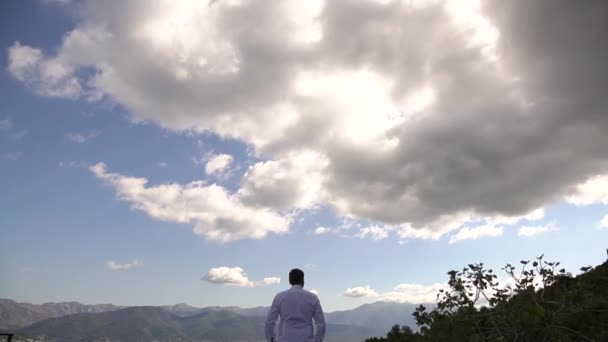 Perast, Montenegro - 10 juli 2020: En man i vit skjorta tittar in i fjärran, bakifrån — Stockvideo