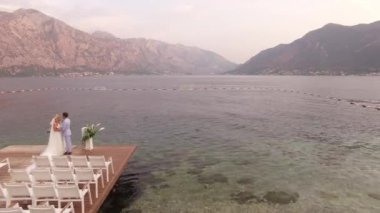 Perast, Karadağ - 11 Temmuz 2020: Gelin ve damat, dağlara bakan deniz kıyısındaki düğün yerinin yanında duruyor