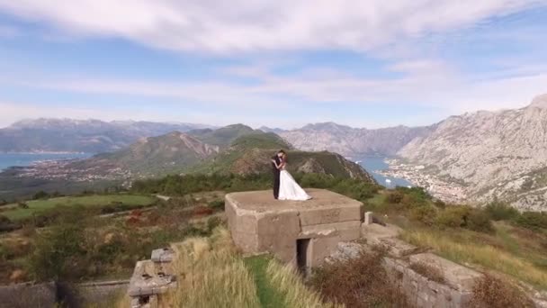 Kotor, Montenegro - 29 de julio de 2020: La novia y el novio se abrazan en el techo del fuerte de Gorazda, detrás de ellos una vista de la bahía de Kotor — Vídeos de Stock