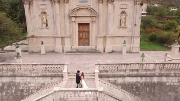 Kotor, Montenegro - 29 de julio de 2020: Los novios se abrazan en las antiguas escaleras de la iglesia de la Natividad de la Santísima Virgen María — Vídeo de stock