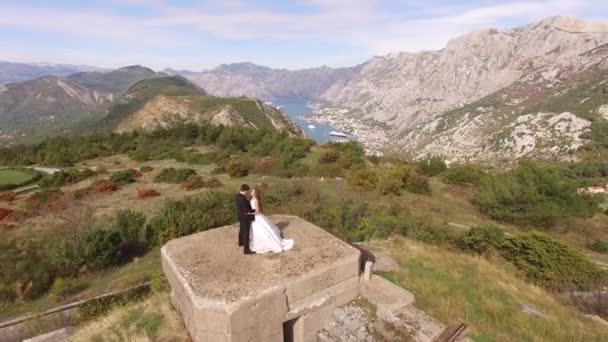 Kotor, Montenegro - 29 de julho de 2020: A noiva e o noivo abraçam no telhado do forte Gorazda, atrás deles uma vista da Baía de Kotor — Vídeo de Stock
