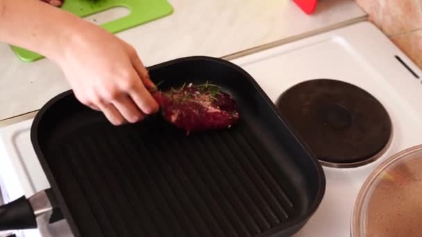 A szakács egy serpenyőbe teszi a steaket a tűzhelyen.. — Stock videók