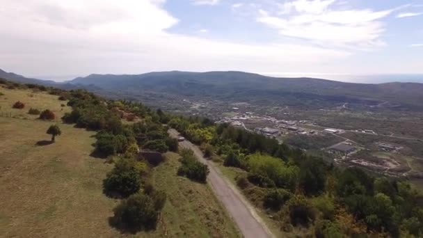 Biały kabriolet jedzie wzdłuż drogi na górze Lovcen na tle malowniczego widoku na Zatokę Kotor — Wideo stockowe