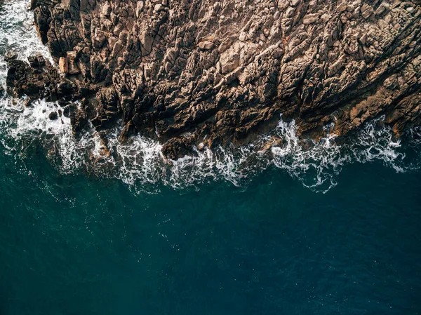 Vista superior del mar azul con olas golpeando en la playa y rocas. — Foto de Stock