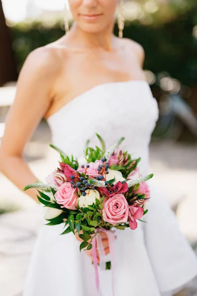 Una novia sofisticada sosteniendo un ramo de bodas con rosas, verónica, viburnum y boj en sus manos, primer plano — Foto de Stock