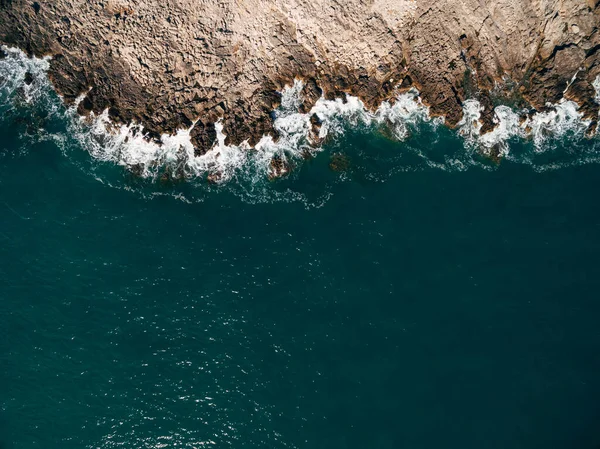 Aérea. Fondo de textura de agua de mar y rocas costeras. Vista superior desde el dron. — Foto de Stock