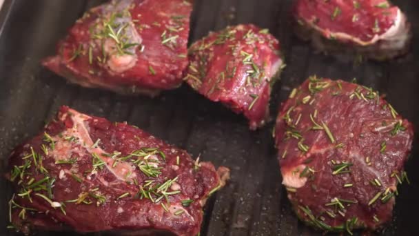 Sappige stukken rode biefstuk worden gestoomd in een grillpan en gebakken bestrooid met rozemarijn. — Stockvideo