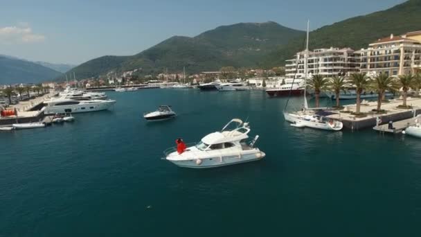 Un homme et une femme en robe rouge se tiennent sur l'avant d'un yacht près de la jetée à Porto Monténégro — Video