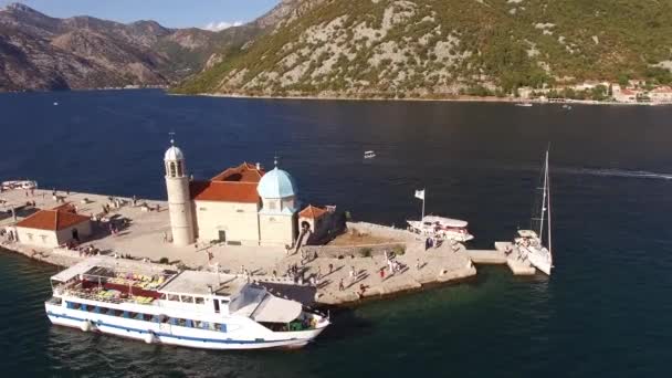 Vista superior da Nossa Senhora das Rochas ilha, iates e barco turístico perto dele na Baía de Kotor — Vídeo de Stock