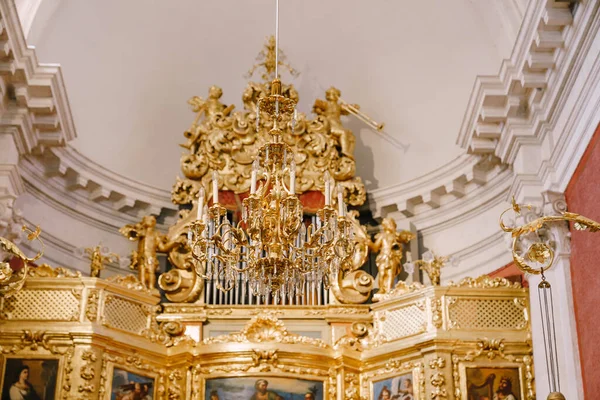 Large golden chandelier with candles in the church against the background of the organ. — Stock Photo, Image