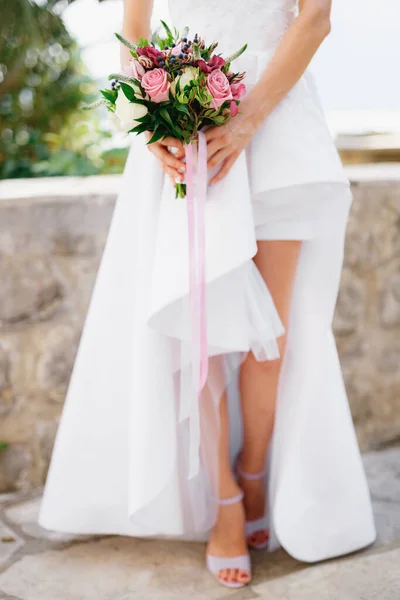 Noiva em um vestido elegante com as pernas abertas segurando um buquê de casamento com rosas, veronica, viburnum e buxo em suas mãos, close-up — Fotografia de Stock