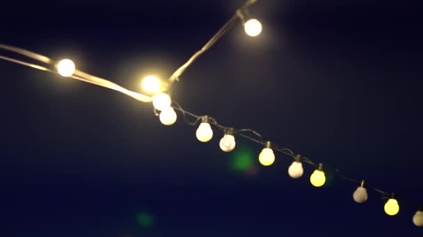Guirlande d'ampoules décoratives incandescentes en soirée à l'extérieur, gros plan — Video