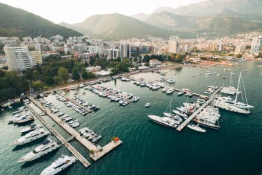 Güneşli bir günde Karadağ 'ın Budva kentinin arka planında park halindeki yatları olan tekne iskelesi