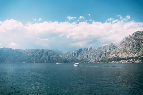 Barco a motor blanco está navegando a lo largo de la bahía de Kotor contra el fondo de las montañas — Foto de Stock