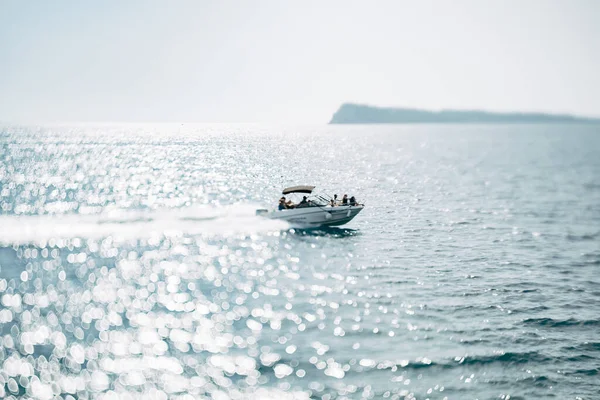 La gente navega en un yate de motor blanco en el mar abierto en un día soleado brillante — Foto de Stock