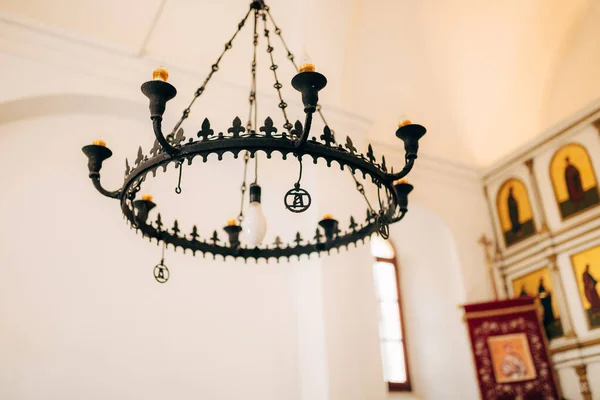 8-light wrought iron black metal chandelier with wax candles in the church. — Stock Photo, Image