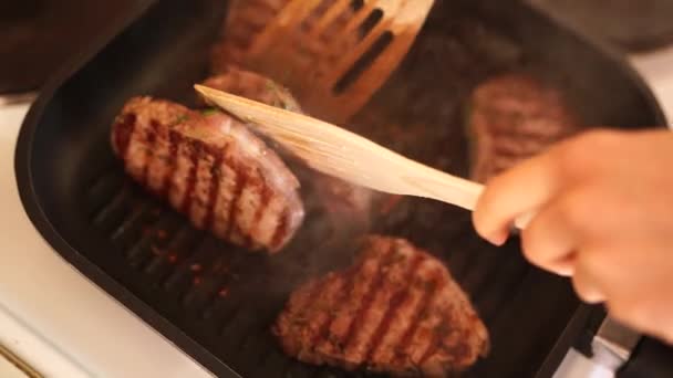 Rauwe biefstuk wordt in een hete grillpan gegooid. Close-up van het vallen van rauw rundvlees biefstuk op de grill pan en rook op de achtergrond. — Stockvideo