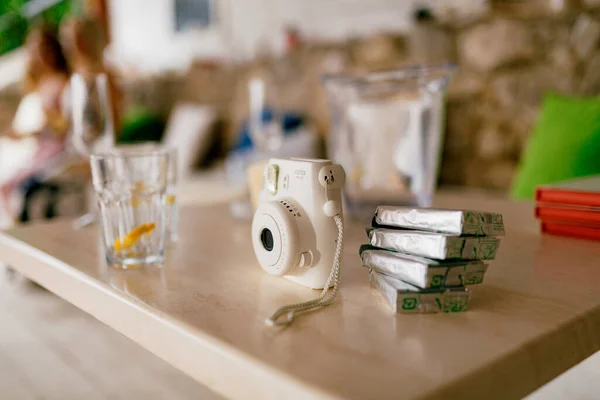 Fujifilm Instax Square SQ1 kamera putih dengan kartrid film cadangan berdiri di atas meja kayu — Stok Foto
