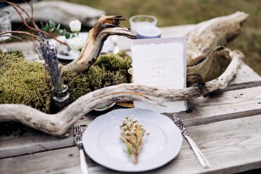 Beyaz kartvizit, çiçekli ve buketli güzel servis edilmiş bir köy masasının üzerinde duruyor.