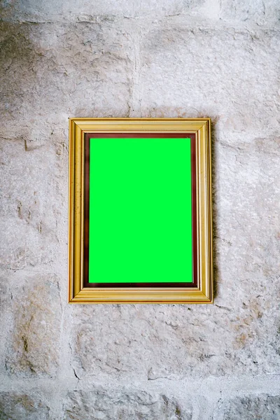 Blank picture in wooden frame hanging on stone wall