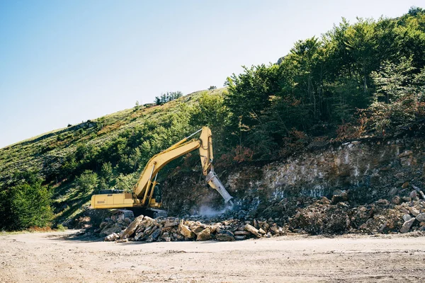 Κίτρινα ίχνη τρακτέρ τρυπάνε πέτρες κοντά στο βουνό. Ευρεία γωνία — Φωτογραφία Αρχείου