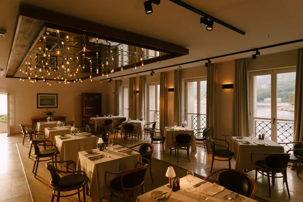 O interior do restaurante é de mesas quadradas, cadeiras e grandes janelas. — Fotografia de Stock