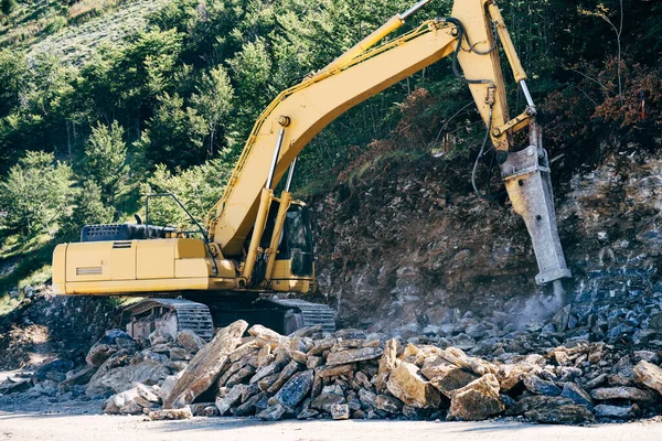 Κίτρινα tractor τρυπάνια πέτρες κοντά στο βουνό — Φωτογραφία Αρχείου