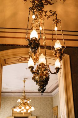 Tavanda bakır avize var. Zincirli antik lambalar. Cam gölgeler ve çiçek desenleri.