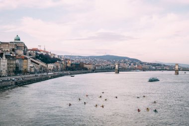 Budapeşte 'deki Tuna Nehri' nin kıyısındaki manzarayı bulutlu mavi bir gökyüzünün arkaplanına doğru izle.