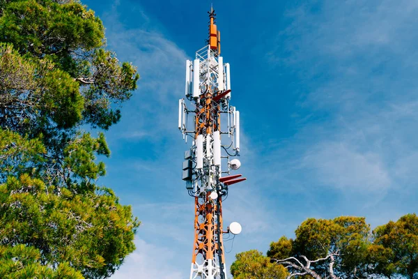 Tour cellulaire sur fond d'arbres verts et de ciel bleu. Gros plan — Photo