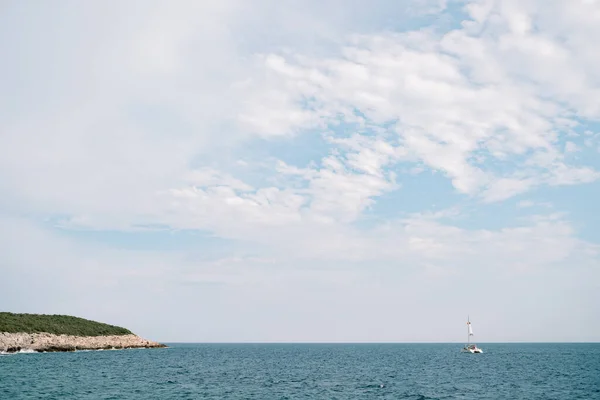 Céu azul com nuvens brancas. Catamarã flutua no mar à distância — Fotografia de Stock