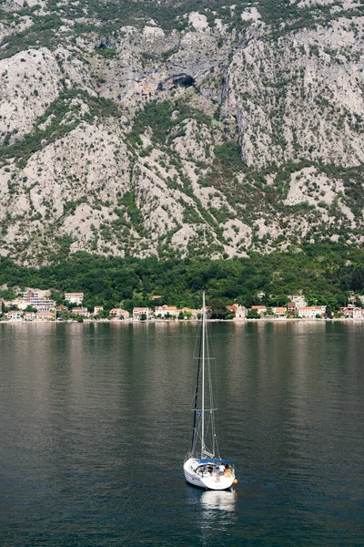 Yate de vela blanca navega a lo largo de la bahía de Kotor contra el telón de fondo de las montañas. Vista trasera —  Fotos de Stock