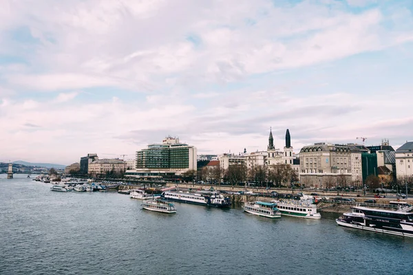 Viele Schiffe auf der Donau in Budapest vor der Kulisse eines wolkenverhangenen blauen Himmels — Stockfoto