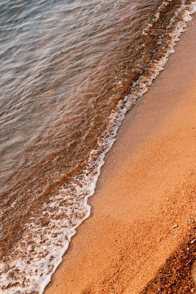 Las olas del mar corren sobre la arena naranja en la playa — Foto de Stock