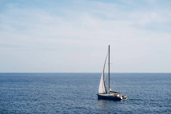 Barco pequeño con una vela blanca revoloteando en las velas del viento en el mar — Foto de Stock