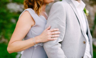 Gri elbiseli gelin, gri takım elbiseli damadın arkasından sarılıyor.