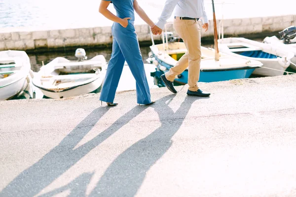 Hombre y mujer están caminando por el muelle tomados de la mano en el fondo de los yates en un día soleado — Foto de Stock