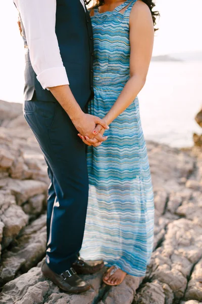 Homme en costume et femme en robe longue avec un support d'ornement sur un rivage de pierre tenant la main — Photo