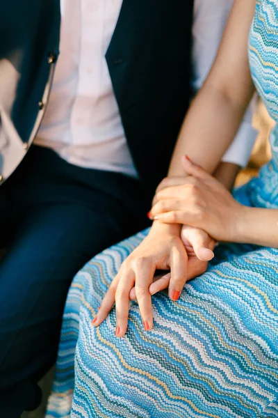 Egy öltönyös férfi és egy csíkos kék ruhás nő egymás kezét fogva ülnek. — Stock Fotó