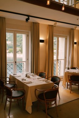 Üst kattan tavana kadar uzanan denize bakan klasik bir restoranın içindeki dikdörtgen masa..