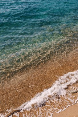 Kumlu bir plajın arka planında deniz dalgaları. Üst görünüm