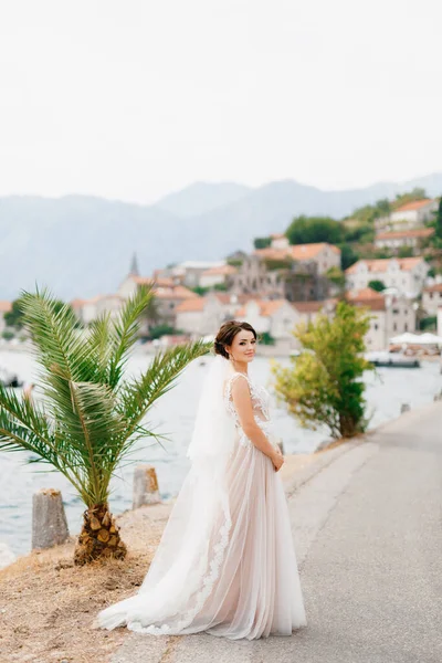 Eine Braut in zartem Kleid und Schleier steht auf der Seebrücke nahe der Altstadt von Perast — Stockfoto