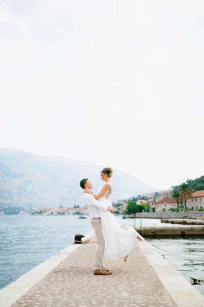 Der Bräutigam umarmt die Braut auf dem Steg in der Bucht von Kotor in der Nähe der gemütlichen Altstadt — Stockfoto