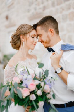 Gelin ve damat eski Perast kasabasında güzel bir tuğla evin yanında el ele tutuşuyorlar.