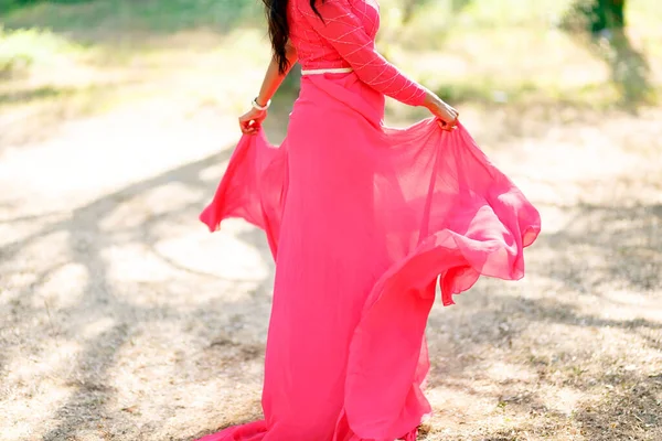 멋진 분홍색 드레스를 입고 긴 스커트를 입은 한 여자가건 조 한 잔디 위에서 돌며 손으로 스커트의 가장자리를 잡고 있다 — 스톡 사진