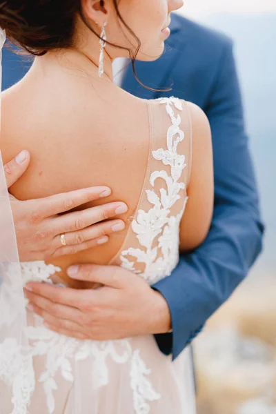 Der Bräutigam umarmt die Braut sanft und streicht ihr mit seinen Händen über den Rücken, Nahaufnahme — Stockfoto