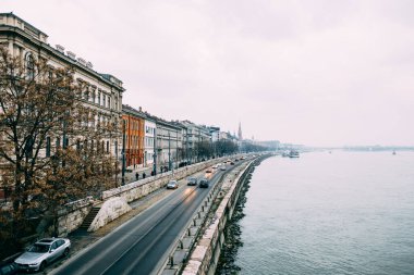 Arabaların Budapeşte 'deki eski evlerin arka planında seyahat ettiği Tuna Nehri' nin setinin manzarası