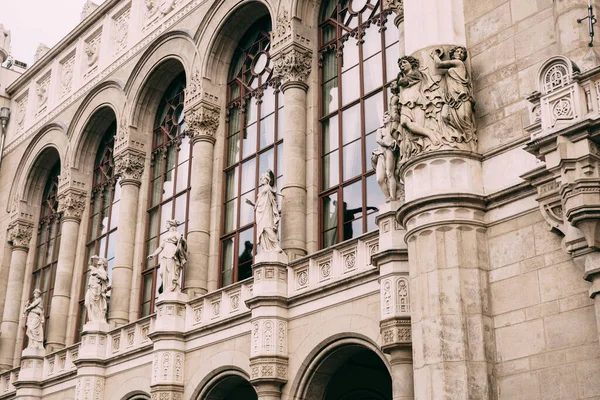 Pěkný výhled na budovu se sochami na fasádě a vysokými klenutými okny v Budapešti — Stock fotografie